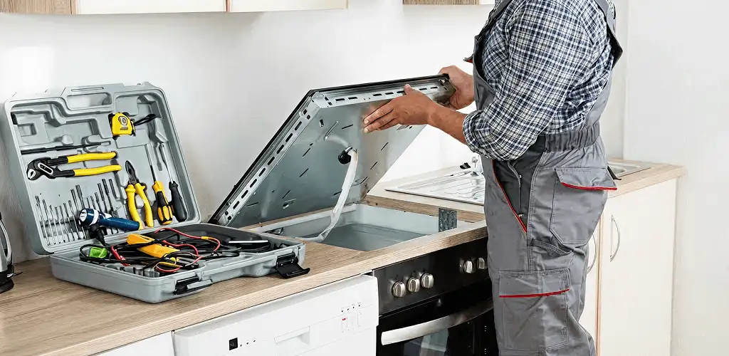 Handyman repairing a cooktop and checking wiring connections in Orange, CA
