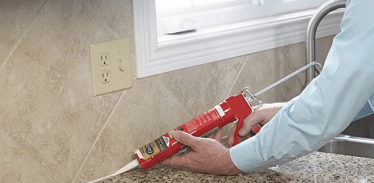 Handyman applying caulk along a kitchen backsplash and countertop seam in Orange, CA