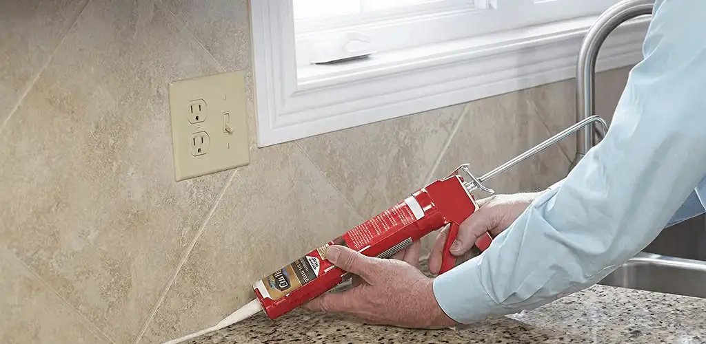 Handyman applying caulk along a kitchen backsplash and countertop seam in Orange, CA