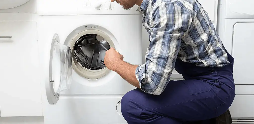 Handyman inspecting a dryer drum and internal parts for repair in Orange, CA