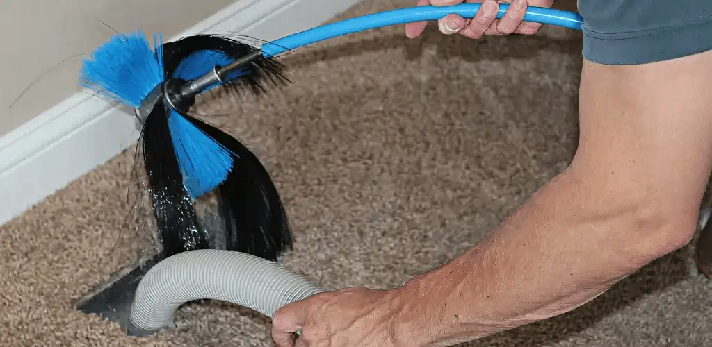 Dryer vent cleaning technician brushing lint from a vent line in Orange, CA