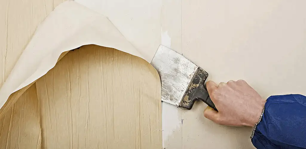 Handyman removing wallpaper with a scraper for wall preparation in Orange, CA