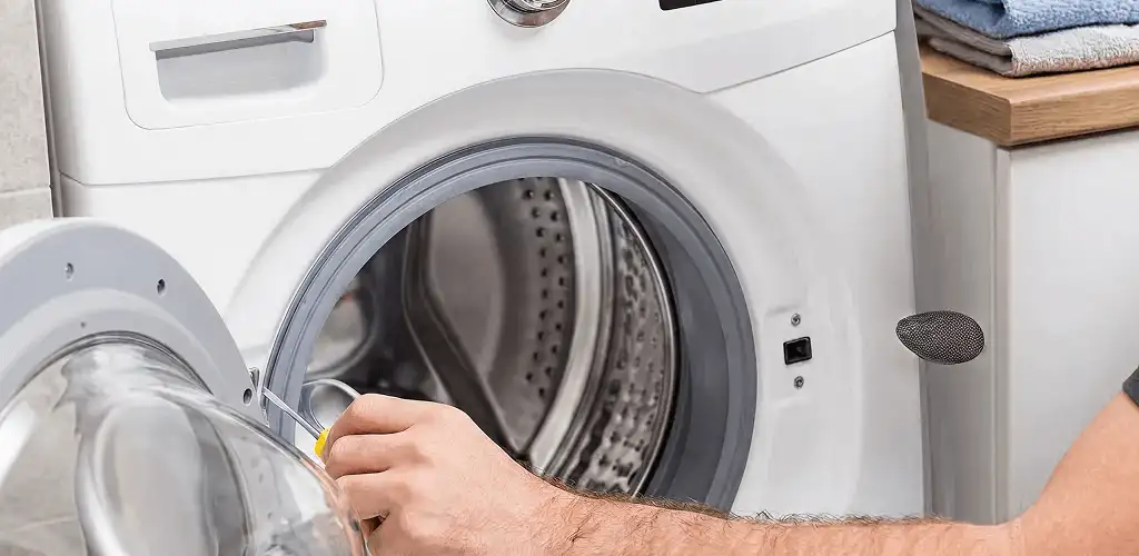 Handyman repairing a front-load washing machine and inspecting the drum in Orange, CA