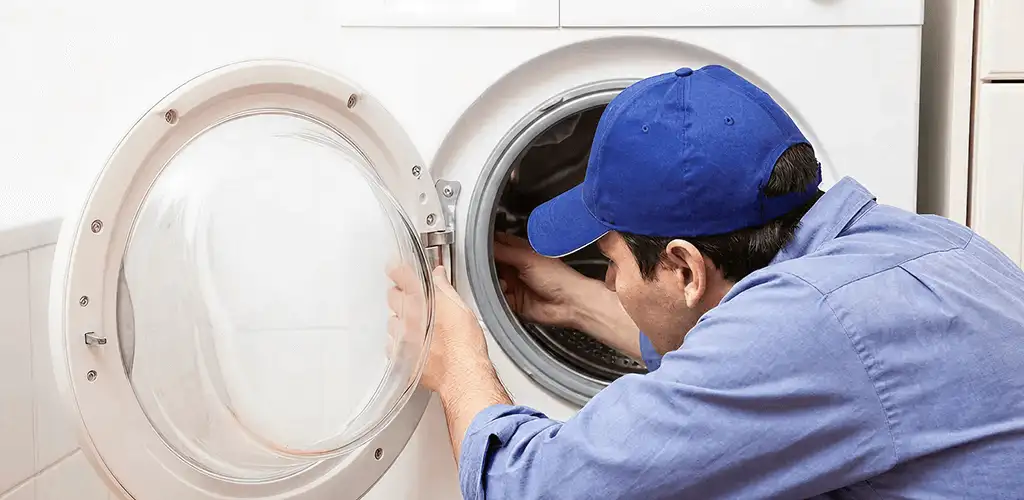 Washing machine repair handyman inspecting a front-load washer drum in Orange, CA