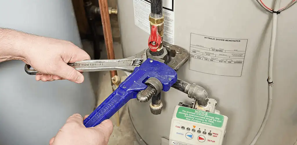 Water heater repair technician tightening the shutoff valve and supply line in Orange, CA